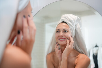 Skincare Concept. A Woman Looking In Mirror Touching Face And Perfect Skin At Bathroom. Selective Focus