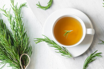 Glass cup of healthy rosemary tea with fresh rosemary bunch on rustic background, winter herbal hot...