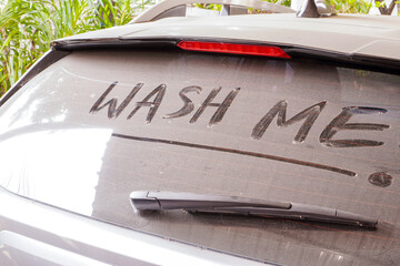 dirty car rear widescreen covered with dust with wording WASH ME , car wash and car care concept , selective focus