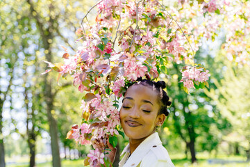 Obraz premium Black african american woman enjoy life and a beautiful park with sakura trees in bloom. Happiness, mental health concept.