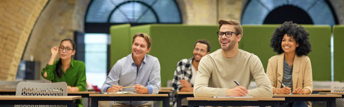 Group of multiracial business people sitting in the modern office and listening to coach or speaker during corporate seminar