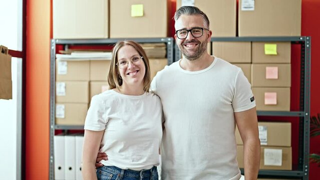 Young Woman And Man Working On Ecommerce Standing Looking At The Camera At Office