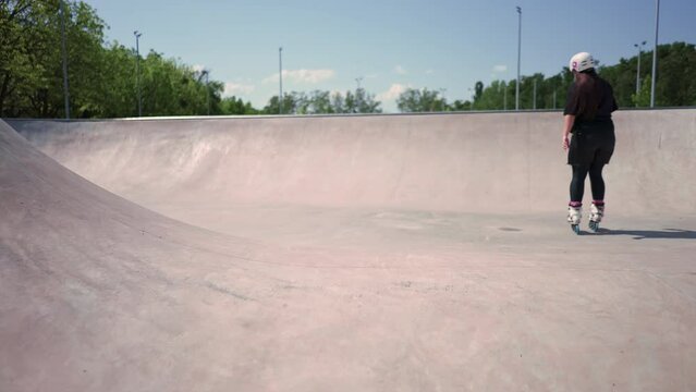 young skilled woman rollerblading and jumping on the ramp in the skate park outside Practicing her tricks or technique of rollerblading for competition