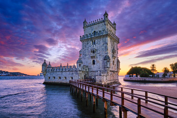 Fototapeta premium Belem Tower or Tower of St Vincent - famous tourist landmark of Lisboa and tourism attraction - on the bank of the Tagus River Tejo in evening dusk after sunset with dramatic sky. Lisbon, Portugal