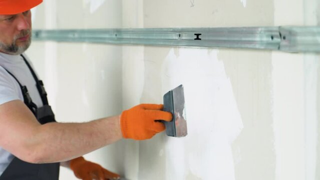 Finishing and Patching Drywall Walls by Caucasian Remodeler in His 45s. Construction Industry