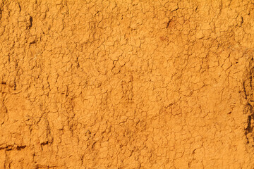 texture of natural orange cracked clay as wall background