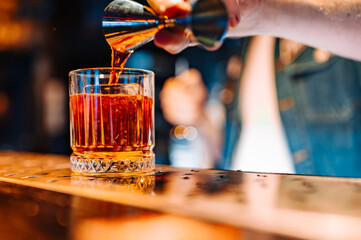 man bartender hand making negroni cocktail. Negroni classic cocktail and gin short drink with sweet vermouth, red bitter liqueur