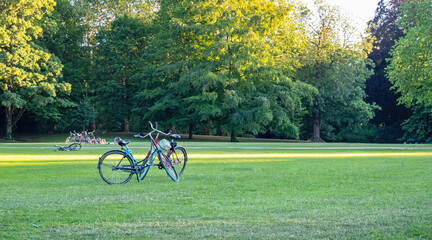 People relaxing after sport on grass at park in Rotterdam Netherlands. Bike parked on green field.