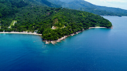 Obraz premium View of the sea and hills. Aerial view of a tropical island. Blue sea, sandy beach, jungle and white clouds over the horizon.