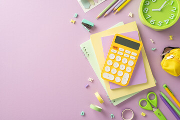 Essential stationery for academic success showcased in this top-view photo featuring copybooks and calculator and other school supplies on a purple backdrop, empty space for text or advertisements