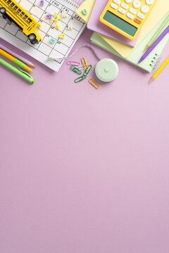 Embark on the educational process with this captivating top-view vertical photograph showcasing schedule, notepads and an array of stationery on isolated violet background. Personalize the copy-space