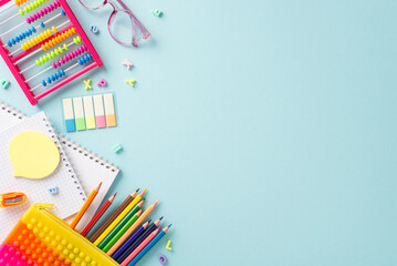 Delightful educational essentials arranged in a top view composition: a vivid assortment of colorful materials on a serene pastel blue background, providing copyspace for text or advertising