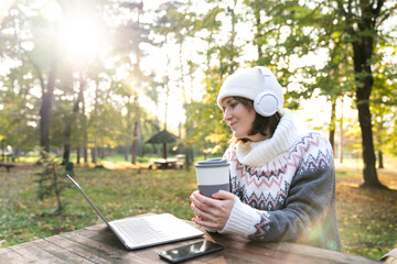 Freelancer working on laptop in autumn park.