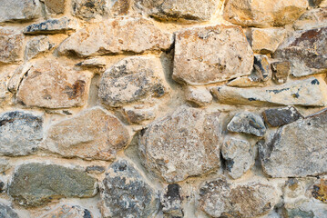 Construction background of large stones and concrete mortar between them, fence of ancient hewn stones, close-up. Ancient vintage wall made of large stones