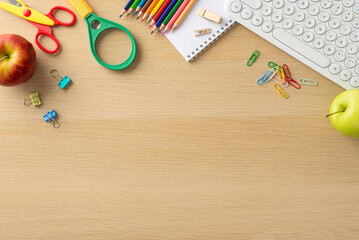 Immerse yourself in digital learning era with this top-view composition, featuring a keyboard, apples, notebook and lots of stationary on wooden backdrop, empty space perfect for text or advertising