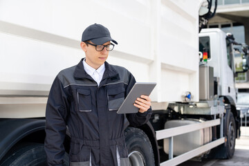 Manager with a digital tablet next to garbage truck.