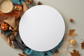 Experience the cozy bliss of autumn at home with this top view photo. Hot coffee, warm blanket, pumpkin candles, maple foliage and spices set the empty circle for text or advert on grey backdrop