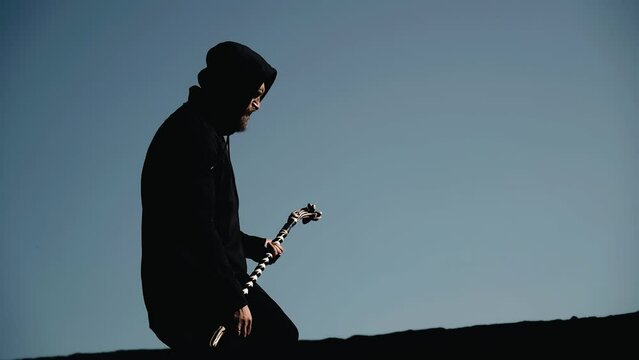 A man in a hoodie and a staff in his hands moves on the roof of an old building.