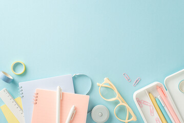 Elevate your education with this top-down image of notepads, pens, paper clips, tape, ruler and...