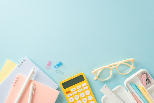 Embark on a successful educational journey with this top-down photograph of meticulously arranged school supplies and calculator on blue background. Use empty space to include text or advertisements