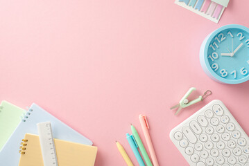 It's back-to-school time! Top-down view of stationery, pens, ruler, notebooks, timer, keyboard and more on pastel pink background. Empty space offers room for educational text or advertisements