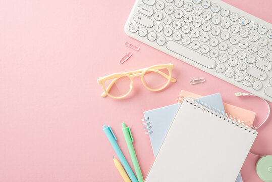 Start school year off right! Stationery, copybooks, pens, glasses, keyboard, clips, measuring tape arranged neatly on a pastel pink surface. Top view provides empty space for text or ads