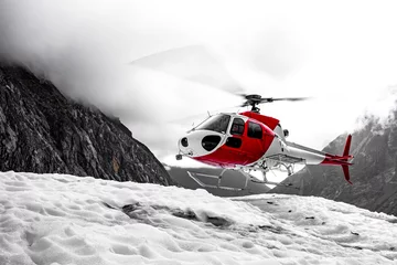 Fototapeten White and red rescue helicopter saving people from a glacier in the mountains © Sven Taubert