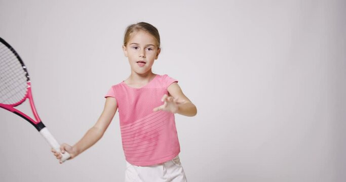 Young female tennis player. Girl in pink sports outfit practicing forehand backhand and volley movement.