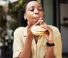 Fotobehang Snackbar Hamburger, fast food and black woman eating a brunch in an outdoor restaurant as a lunch meal craving deal. Breakfast, sandwich and young female person or customer enjoying a tasty unhealthy snack