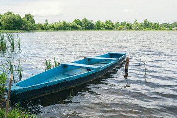 A wooden boat on the shore of the lake. Old boat for swimming. A wooden boat for fishing on the lake