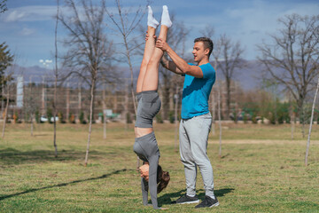 Flexible, fit girl standing on her arms while her male friend is holding her legs