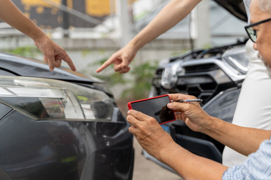A male car insurance agent using his phone to take picture of the car scratch marks from the accident while the male and female car owners pointing them out