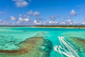 Aerial view of two jet skies passing coral reef sea at Maldives sunny island coast. Amazing travel landscape aerial beach vacation. Sunshine palm trees exotic blue bay. Peaceful bright tropical nature