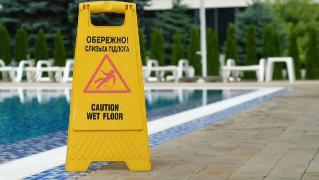 Yellow sign warning that the pool floor is slippery.