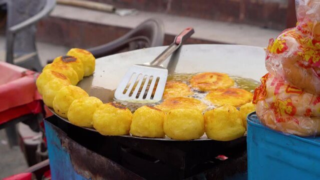 aloo potato tikki cutlets frying in a shallow pan with oil as more are kept on the side showing amazing street food in India during the monsoons