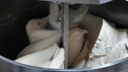 Two bakers knead the dough for bread in a dough mixer in an industrial bakery. Production of bakery products.