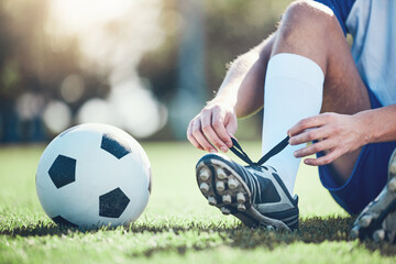 Ball, man and soccer player tie shoes for training, fitness games and performance on field. Closeup, football athlete and lace sneakers on feet, grass pitch and sports competition on stadium ground