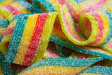 Colorful jelly candies strips in sugar sprinkles. Sour flavored rainbow candy background.