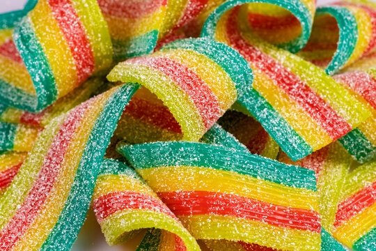 Colorful jelly candies strips in sugar sprinkles. Sour flavored rainbow candy background.