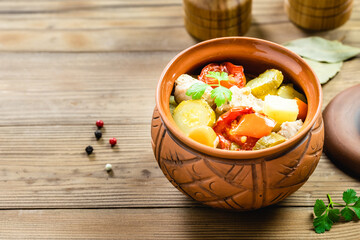 Stewed turkey and vegetables in a pot on wooden background. Top view, flat lay, copy space.