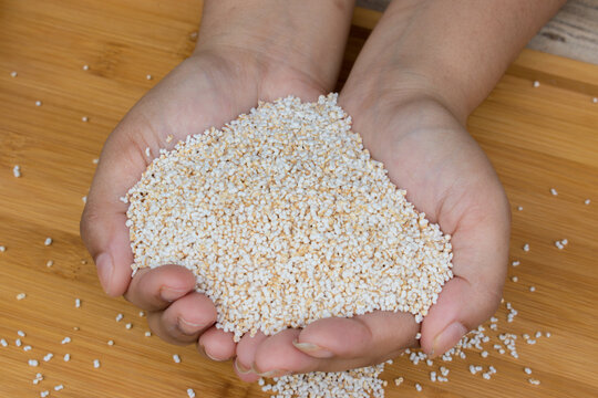 Hand holding puffed amaranth or ramdana or rajgira on a wooden tray. It is a gluten free grain that provides fiber, protein and micronutrients. 