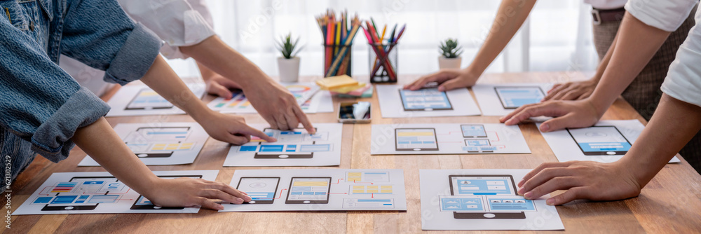 Poster Panorama shot of front-end developer team brainstorming UI and UX designs for mobile app on paper wireframe interface. User interface development team planning for user-friendly UI design. Scrutinize