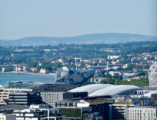 view of the district of confluences in Lyon with the very modern architecture of the confluence museum and in the background the Lyon countryside and its hills in summer.