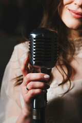 Unrecognizable young female singer holding modern microphone, closeup. Woman singing. Faceless person. Concept of live performance or concert