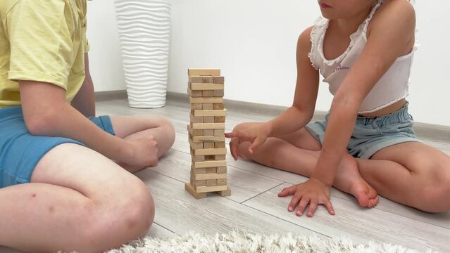children and grandmother play a tower of wooden blocks at home, happy grandmother and grandchildren build a tower of wooden blocks, jenga game,