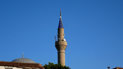 The building of a Muslim mosque with a blue tower against a blue sky. Prayer house for Muslims and adherents of Islam