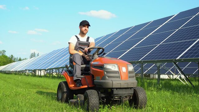 Staff in the solar photovoltaic panels with mowers cut weeds