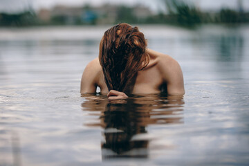 Portrait of naked woman swimming in the lake or river hiding behind hair