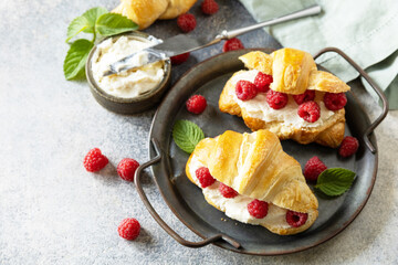 Healthy food dessert concept, french pastry. Tasty freshly baked croissants with cream cheese and raspberry on a stone background. Copy space.