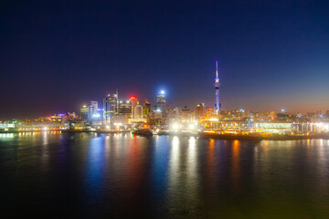 Night city of Auckland New Zealand. Glowing skyscrapers, bay and seaport of Auckland.